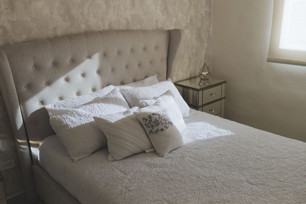 Bed with a tufted headboard and a mirrored bedside table (illustrative stock image)