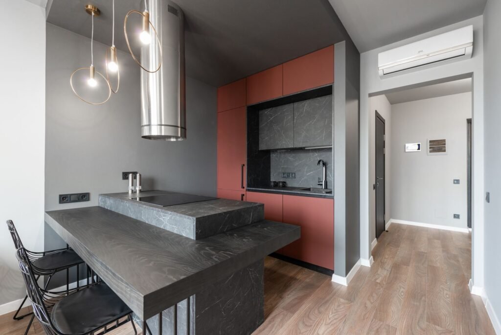 Kitchen with a breakfast counter, pendant lamps and chimney (illustrative stock image)