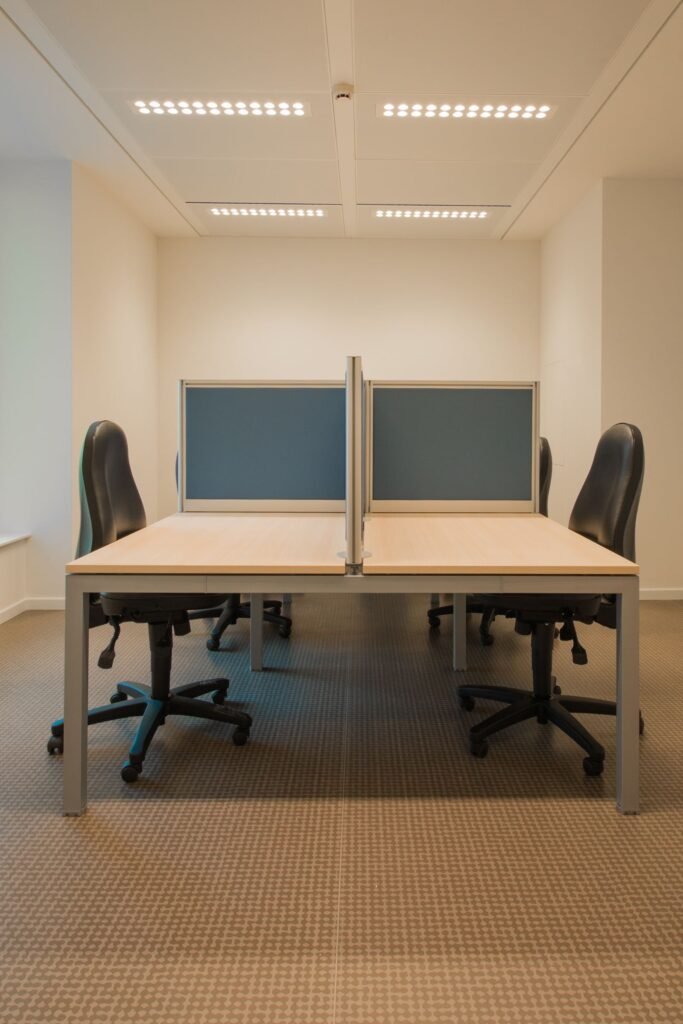 Partitioned office desks with rolling chairs (illustrative stock image)