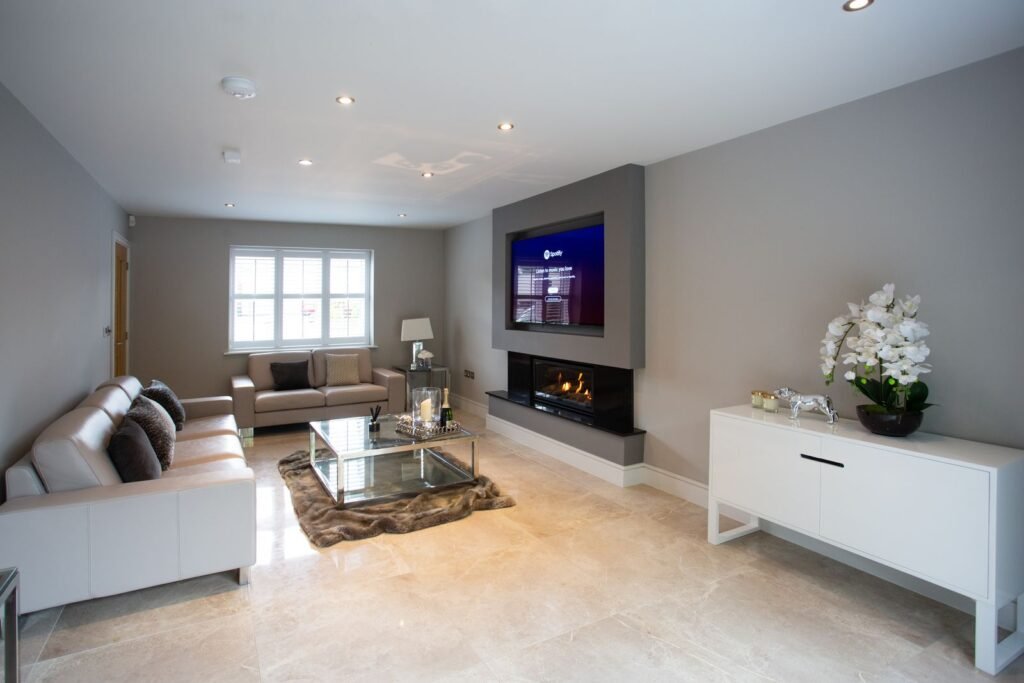 Living room with a TV set above a wall-mounted fireplace and white sideboard (illustrative stock image)