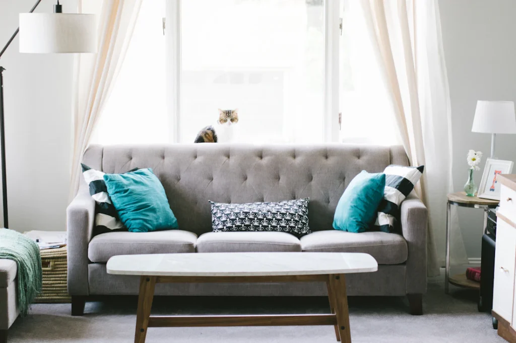Living room with grey tufted sofa and teal cushions (illustrative image)